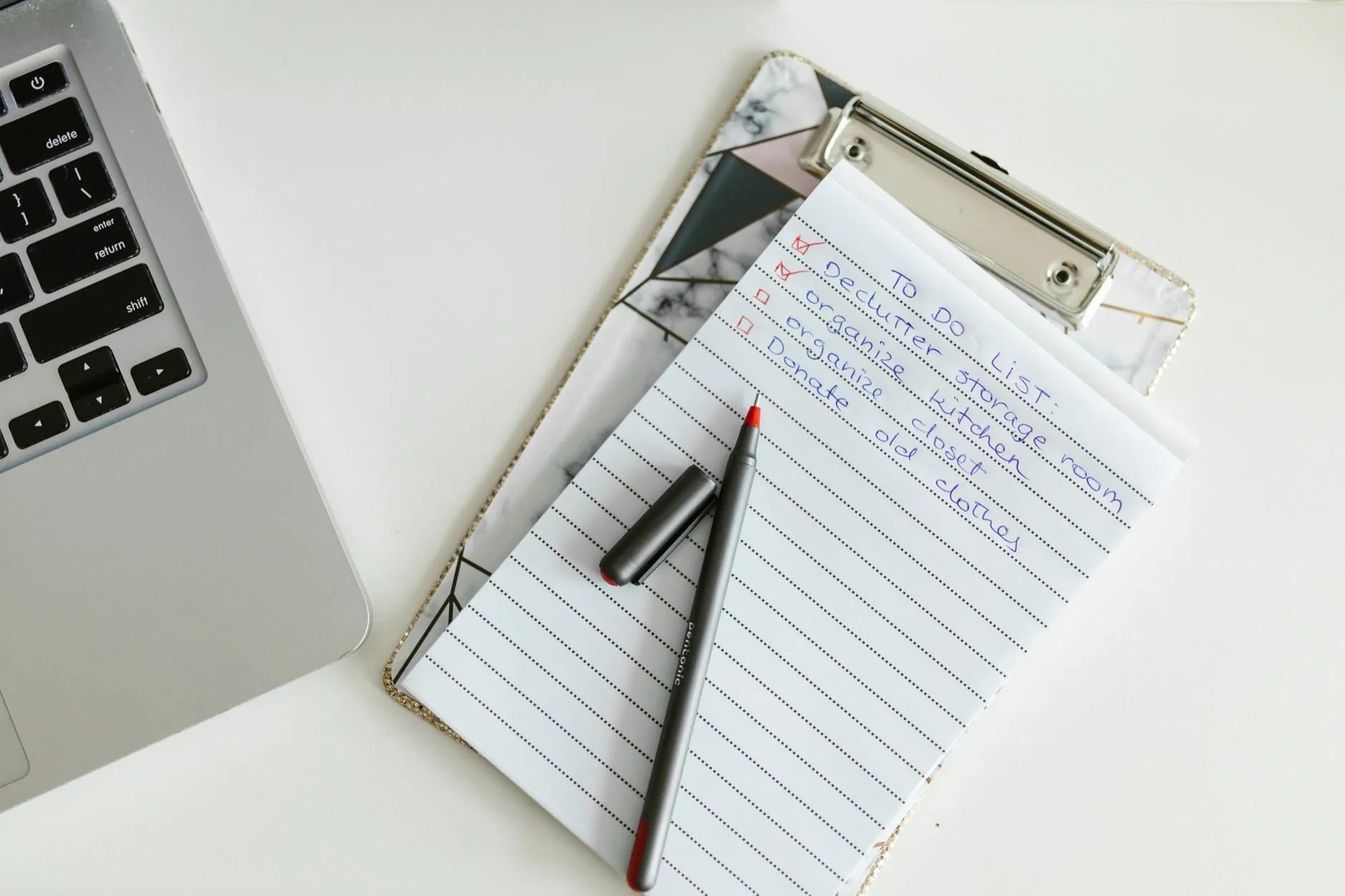 A clipboard and notepad with a pen on a desk