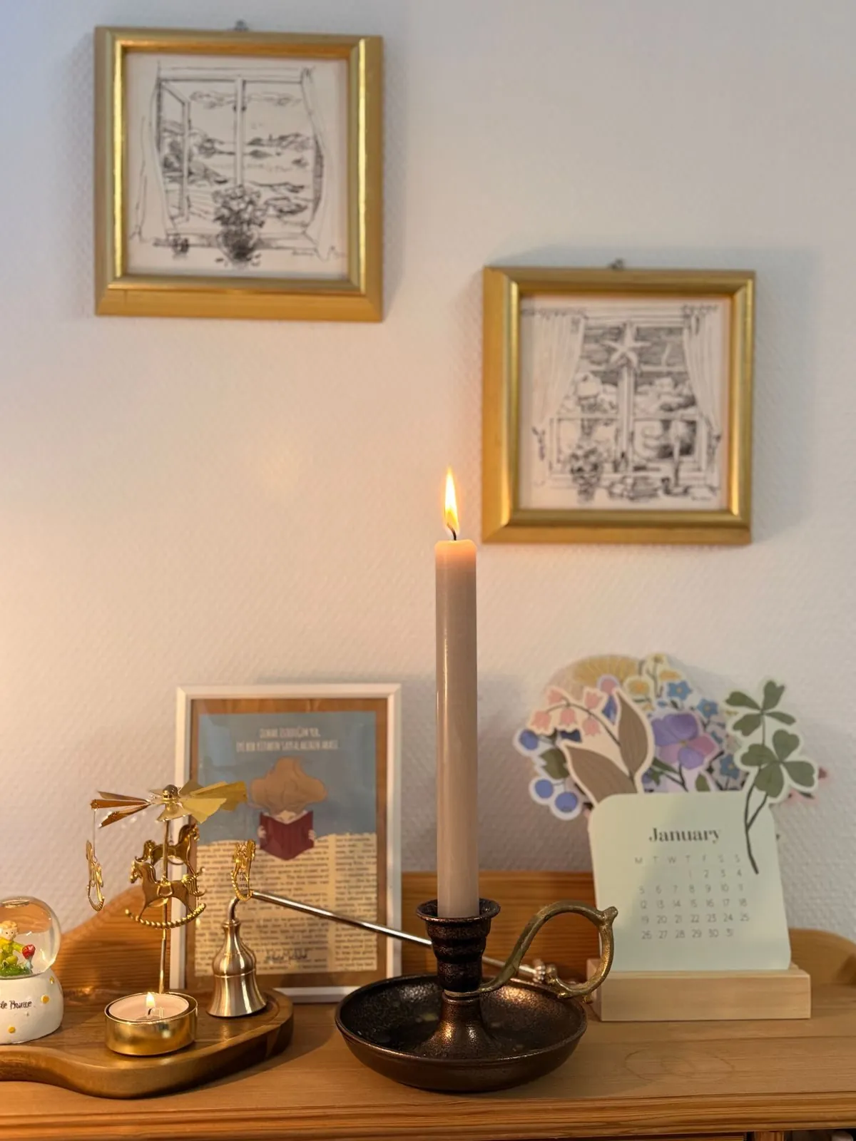 A wall calendar in a kitchen with a candle and flowers