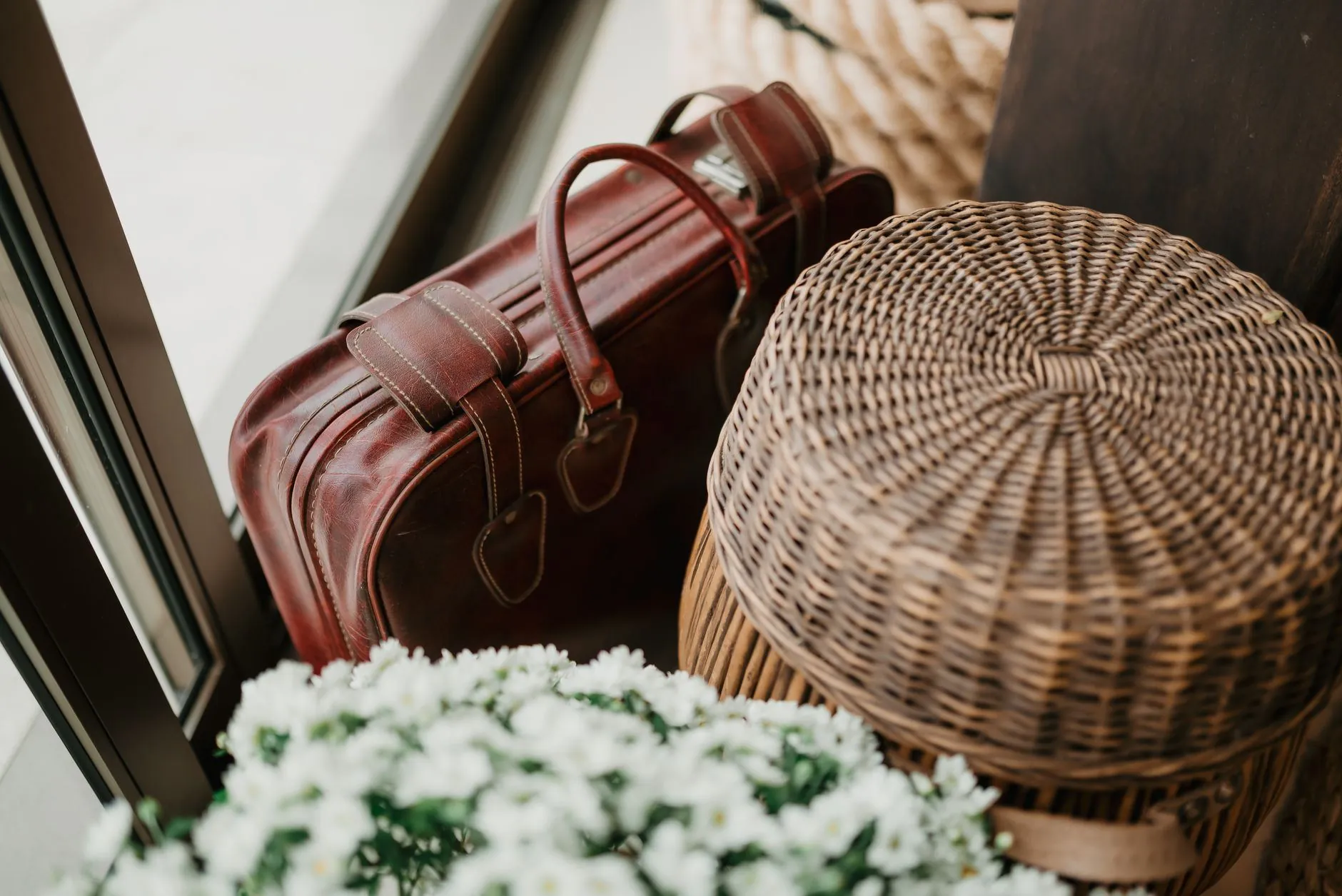 A packed leather bag and a wicker basket by a door