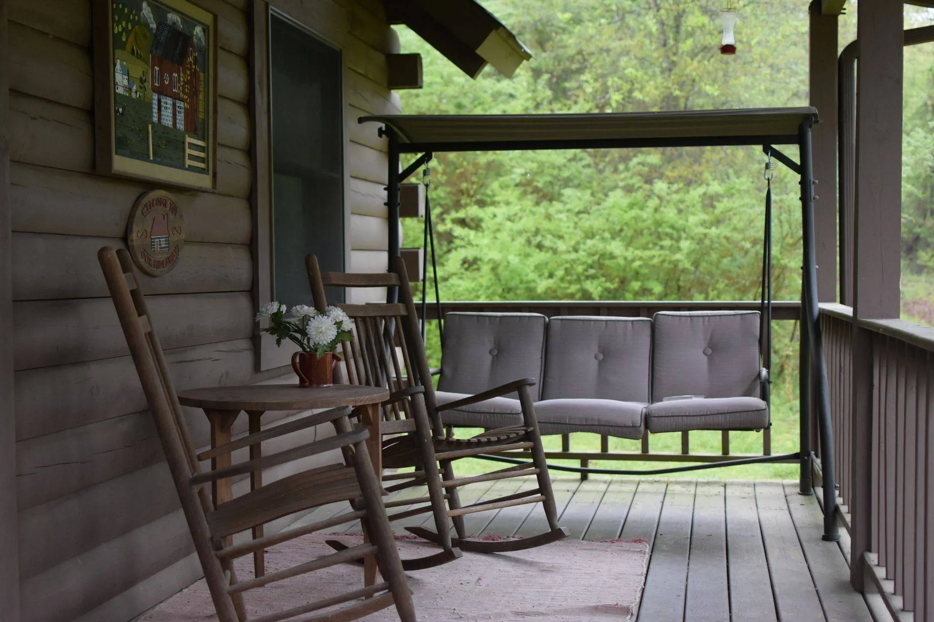 A covered porch with rocking chairs and a swing