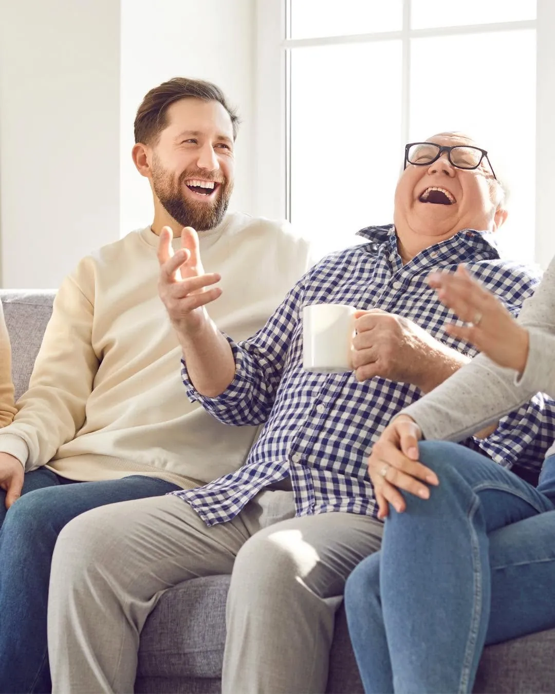 A man and an older man laughing together on the couch